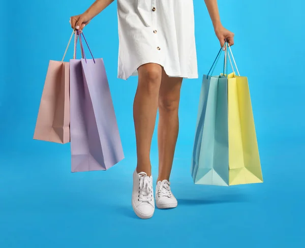 Junge Frau Mit Papiereinkaufstaschen Auf Hellblauem Hintergrund Nahaufnahme — Stockfoto