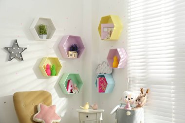 Çocuk odasındaki beyaz duvarda altıgen şekilli raflar. İç tasarım