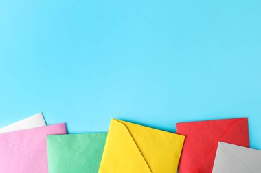 Açık mavi arkaplanda renkli zarflar, düz bir zemin. Metin için boşluk