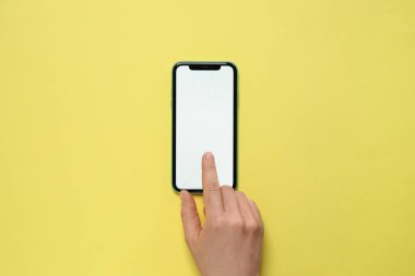MYKOLAIV, UKRAINE - Temmuz 07, 2020: Sarı arka planda iPhone 11 kullanan kadın, üst görünüm. Tasarım için model
