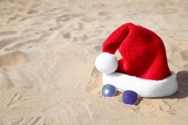 Noel Baba 'nın şapkası ve güneş gözlüğü kumsalda, mesaj için yer var. Noel tatili