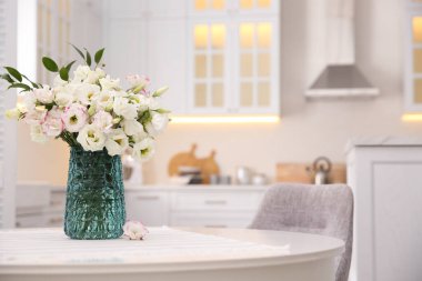 Mutfaktaki masada bir buket güzel çiçek, mesaj için yer var. İç tasarım