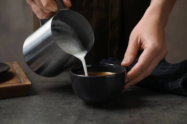 Vrouw Gieten Melk Kopje Koffie Aan Grijze Tafel Close — Stockfoto