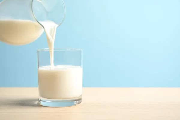 Verter Leche Vaso Sobre Una Mesa Madera Sobre Fondo Azul —  Fotos de Stock