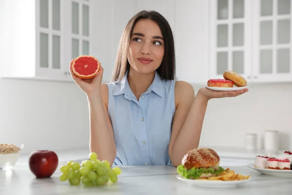 Женщина Выбирает Между Грейпфрутом Пончиками Кухне — стоковое фото