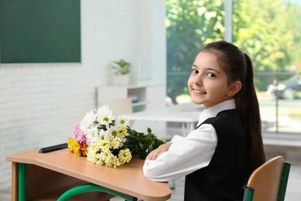 Szczęśliwa Uczennica Bukietem Siedząca Przy Biurku Klasie Dzień Nauczyciela — Zdjęcie stockowe
