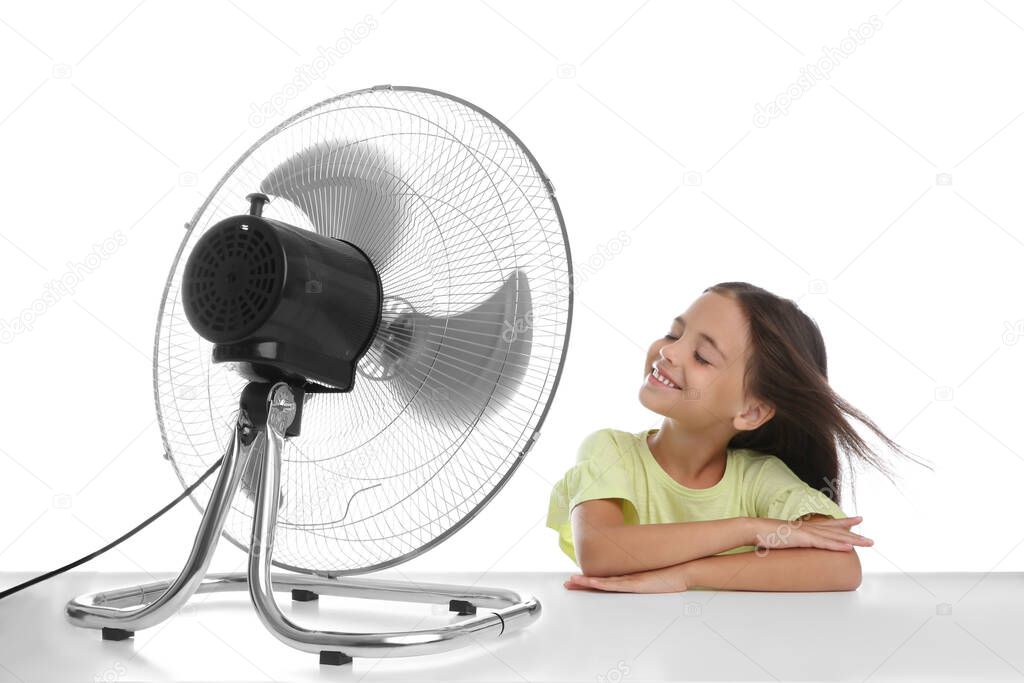 Little girl enjoying air flow from fan on white background. Summer heat