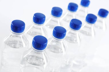 Beyaz arka planda saf su bulunan plastik şişeler, yakın plan.