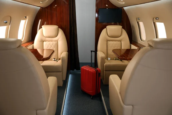 Airplane cabin with red suitcase. Air travel