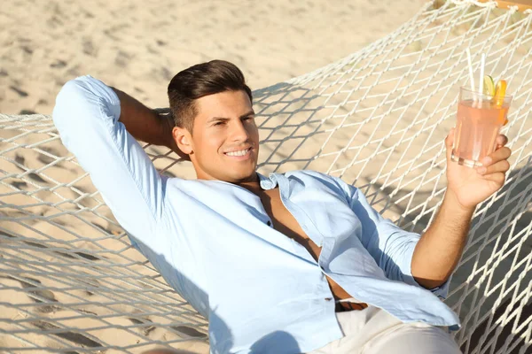 Sahilde hamakta dinlenen ferahlatıcı kokteyli olan adam.