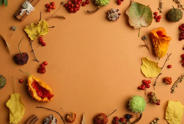 Dried flowers, leaves and berries arranged in shape of wreath on brown background, flat lay with space for text. Autumnal aesthetic