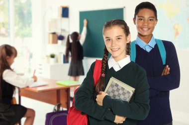 Sınıfta sırt çantalı mutlu gençler.