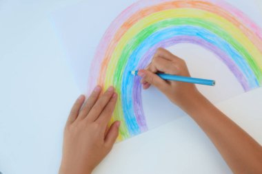 Beyaz arka planda gökkuşağı çizen küçük çocuk, üst manzara. Ev konseptinde kal
