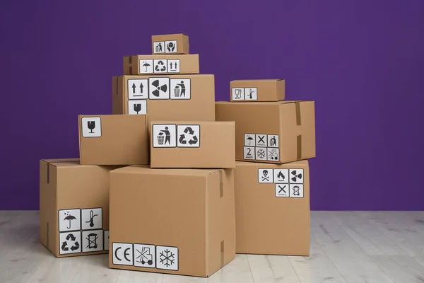 Cajas Cartón Con Diferentes Símbolos Embalaje Suelo Cerca Pared Púrpura — Foto de Stock