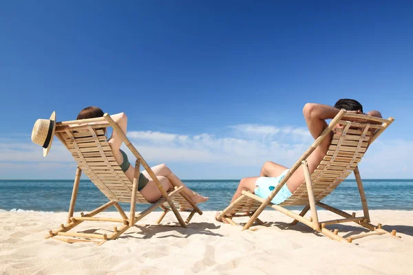 穿着比基尼的女人和她的男朋友坐在海滩的躺椅上 可爱的夫妻 — 图库照片