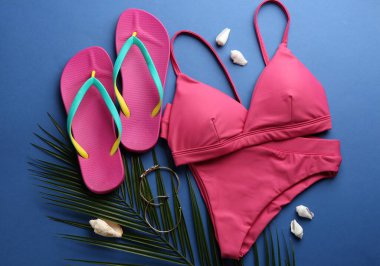 Güzel pembe bikini ve plaj aksesuarları mavi arka planda, düz yatıyordu.