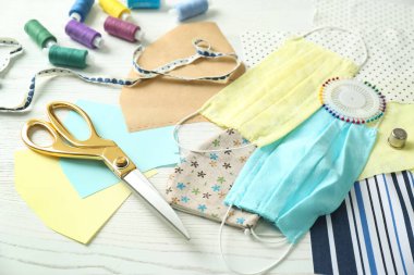 Kumaş, aksesuar ve bez maskeler beyaz ahşap masada. COVID-19 salgını sırasında kişisel koruma ekipmanları