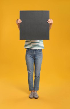 Sarı arka planda siyah boş poster tutan bir kadın. Tasarım için model