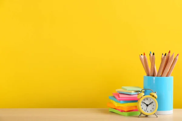 不同的学校文具和闹钟放在桌上的黄色背景 空白处 回学校去 — 图库照片