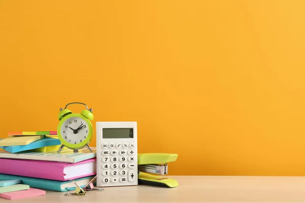 Verschiedene Schulsachen Und Wecker Auf Tisch Vor Orangefarbenem Hintergrund Platz — Stockfoto