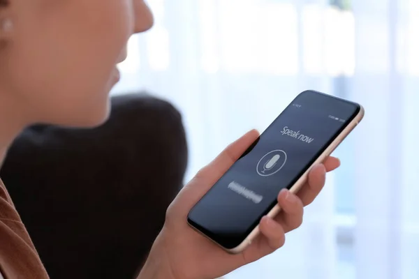 Woman using voice search on smartphone indoors, closeup