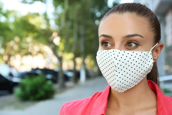 Woman wearing handmade cloth mask outdoors, space for text. Personal protective equipment during COVID-19 pandemic