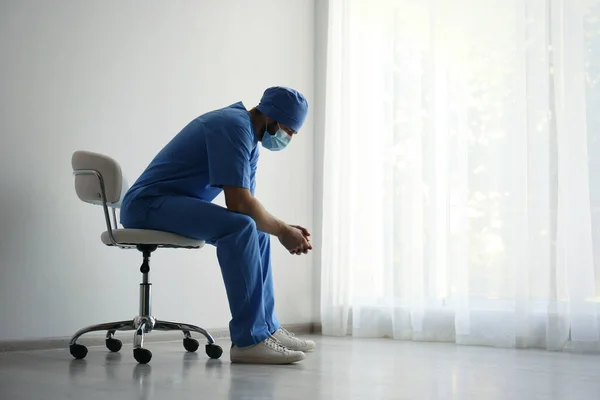 stock image Exhausted doctor sitting on chair indoors, space for text. Stress of health care workers during COVID-19 pandemic