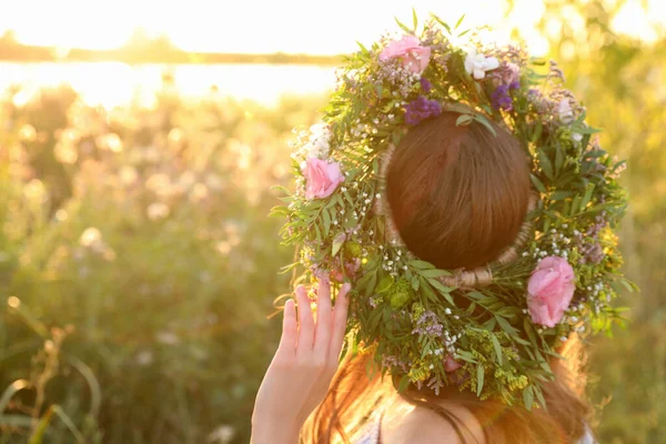 晴れた日に屋外で美しい花で作られた花輪を身に着けている若い女性 — ストック写真