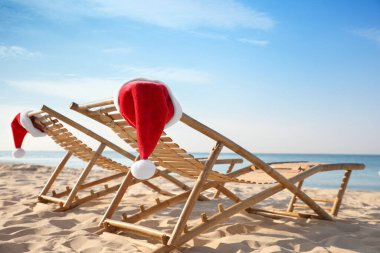 Plajda Noel Baba 'nın şapkalarıyla güneşleniyorlar. Noel tatili