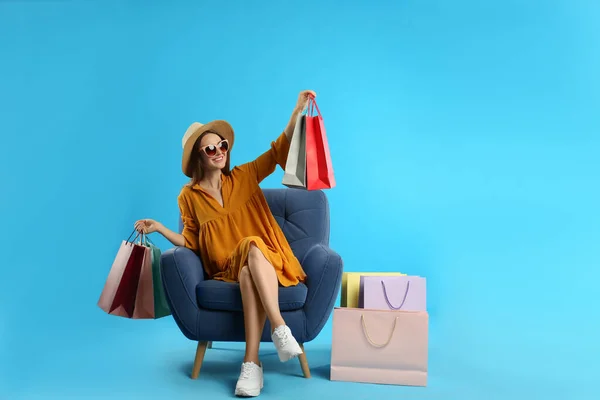 Hermosa Mujer Joven Con Bolsas Papel Sillón Sobre Fondo Azul —  Fotos de Stock