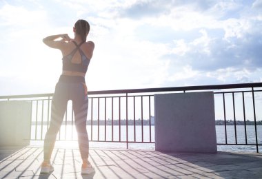 Genç bir kadın sabahları nehir kıyısında iskelede geriniyor. Metin için boşluk