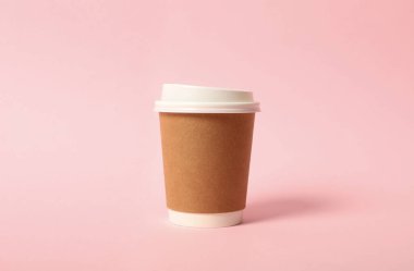 Pembe arka planda paket kağıttan kahve fincanı.