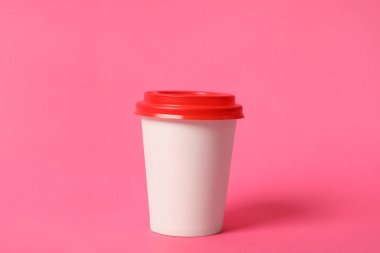 Pembe arka planda paket kağıttan kahve fincanı.