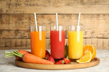 Lezzetli meyve suları ve beyaz ahşap masada taze malzemeler.