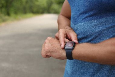 Akıllı saat ile adam kontrol zaman aralığı, mesafe, kalp atış hızı ve yanmış kalori miktarı fitness monitör uygulaması açık havada eğitim sonra, yakın