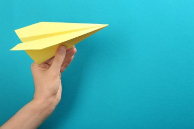 Açık mavi arka planda kağıt uçak tutan kadın, yakın plan. Metin için boşluk