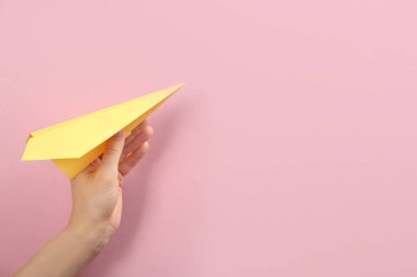 Pembe arka planda kağıt uçak tutan kadın, yakın plan. Metin için boşluk