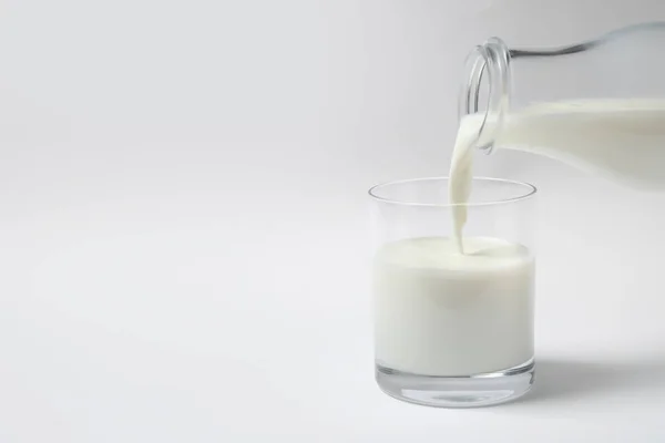 将牛奶倒入白底玻璃杯中 — 图库照片