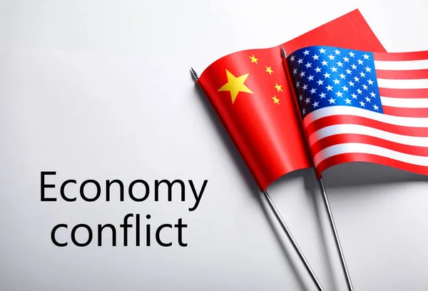 USA and China flags near words ECONOMY CONFLICT on white background, flat lay