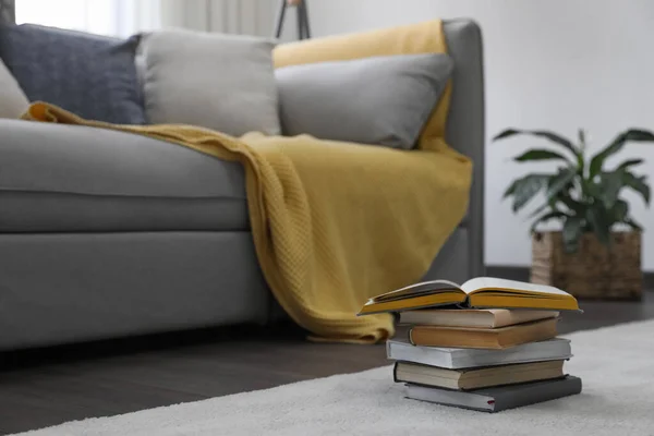 Stack of books near sofa in living room. Interior design