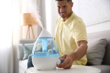 Evdeki modern hava nemlendiricisini kullanan adam, eline odaklan.