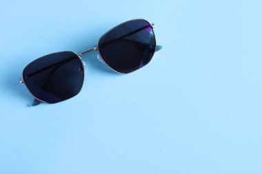 Açık mavi arka planda şık güneş gözlükleri, üst manzara. Metin için boşluk