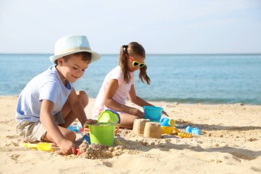 Kumsalda plastik oyuncaklarla oynayan sevimli çocuklar.