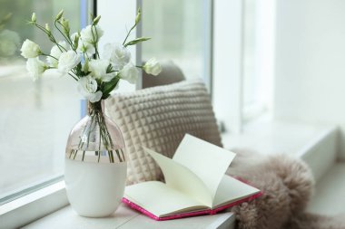 Taze çiçekli şık vazo ve pencere pervazında kitap