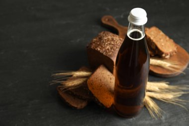 Bir şişe taze kvass, dikenler ve gri masada ekmek, yakın plan. Metin için boşluk