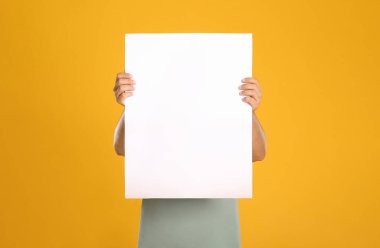 Sarı arka planda beyaz boş poster tutan adam. Tasarım için model