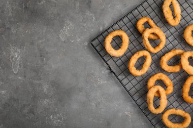 Gri masada kızarmış soğan halkaları ile soğutma rafı, üst manzara. Metin için boşluk