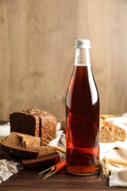 Lezzetli bir şişe taze kvass, dikenler ve ahşap masada ekmek.