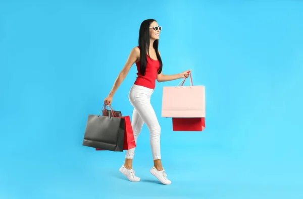 Schöne Junge Frau Mit Papiereinkaufstaschen Auf Hellblauem Hintergrund — Stockfoto
