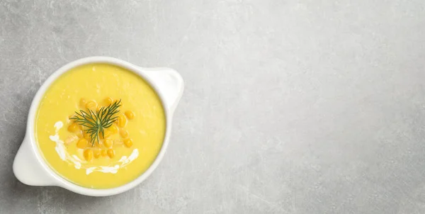 Delicious creamy corn soup on grey table, top view. Space for text
